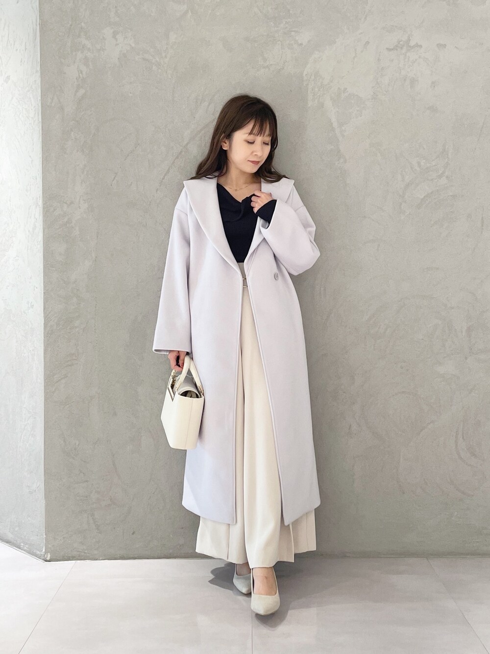 ホワイト系のハンドバッグ、ホワイト系のパンプス、ブルー系のニット/セーターを着用したレディースの秋コーディネートの4枚目の写真