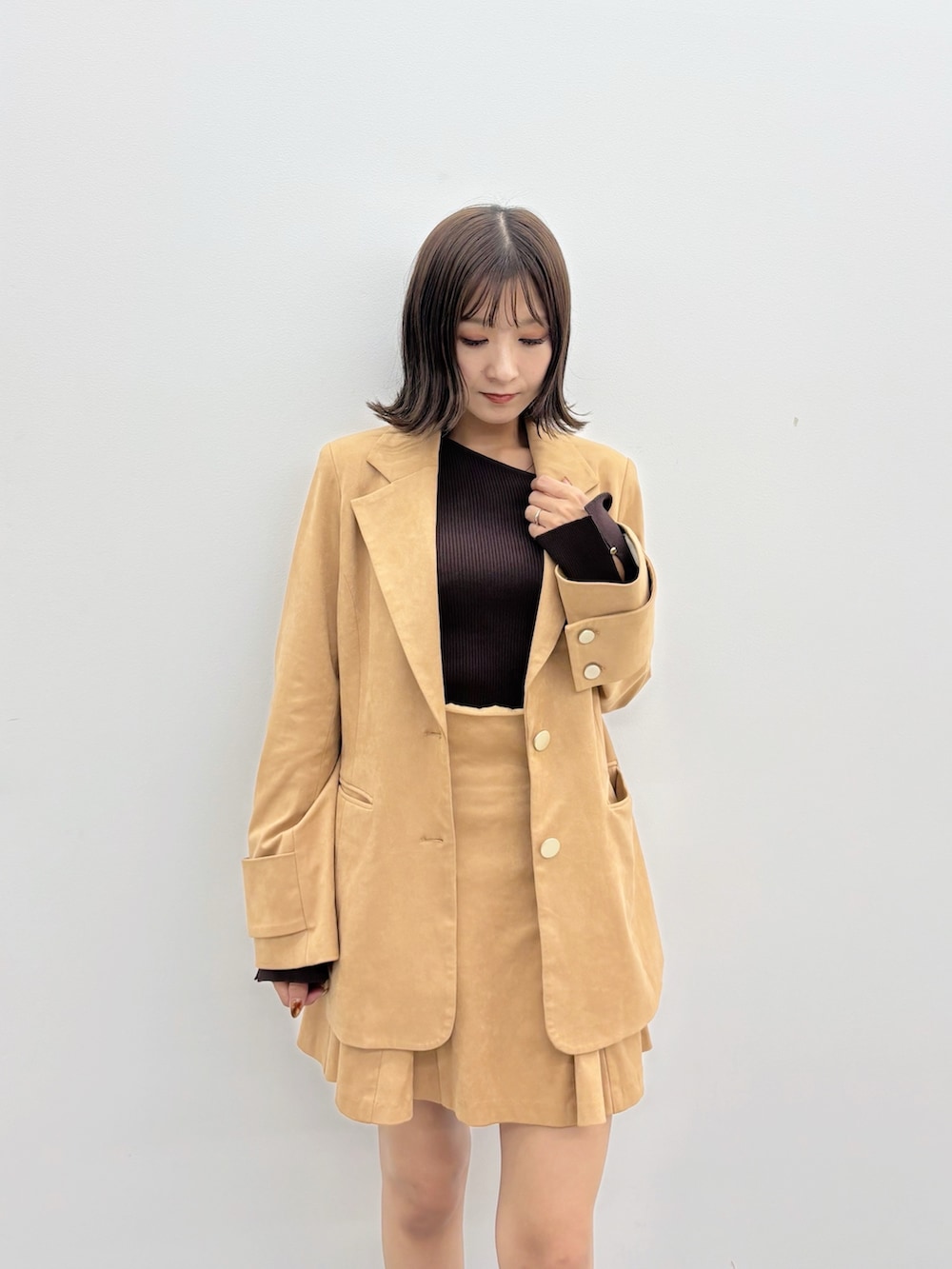 ブラウン系のニット/セーター、ブラウン系のスカート、ブラウン系のテーラードジャケットを着用したレディースの秋コーディネートの4枚目の写真