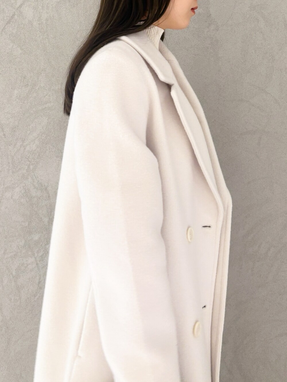 ホワイト系のチェスターコート、ブラック系のブーツ、ブラウン系のハンドバッグを着用したレディースの冬コーディネートの5枚目の写真