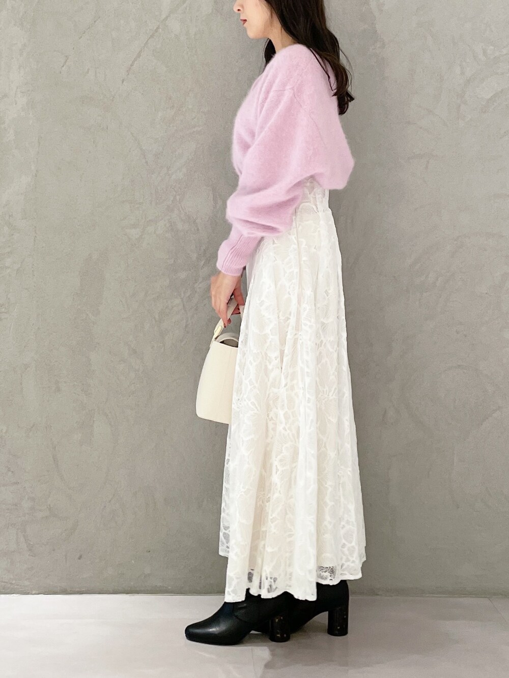 ホワイト系のハンドバッグ、ブラック系のブーツ、ホワイト系のスカートを着用したレディースの秋コーディネートの3枚目の写真
