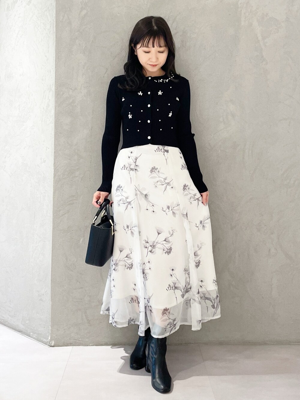 ブラック系のハンドバッグ、ブラック系のブーツ、ホワイト系のスカートを着用したレディースの冬コーディネートの5枚目の写真