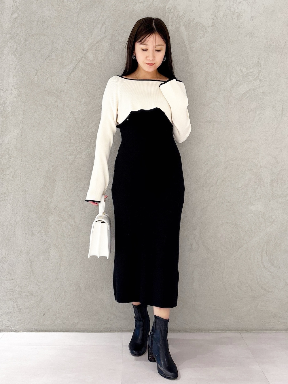 ブラック系のブーツ、ホワイト系のハンドバッグ、ブラック系のワンピースを着用したレディースの冬コーディネートの6枚目の写真