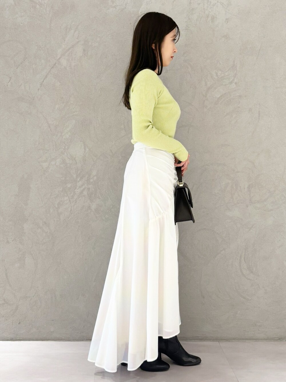 ホワイト系のスカート、ブラック系のブーツ、ブラウン系のハンドバッグを着用したレディースの冬コーディネートの3枚目の写真