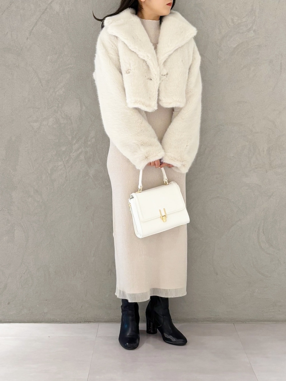 ホワイト系のワンピース、ブラック系のブーツ、ホワイト系のハンドバッグを着用したレディースの冬コーディネートの2枚目の写真