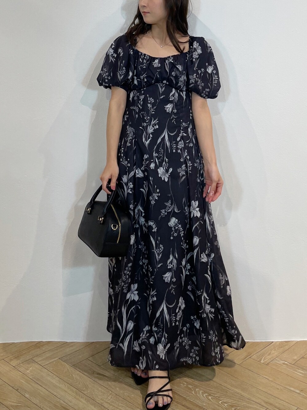 ブラック系のハンドバッグ、ブラック系のサンダル、グレー系のワンピースを着用したレディースの春コーディネートの6枚目の写真