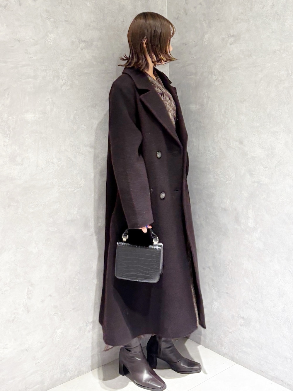 ブラウン系のチェスターコート、ブラウン系のワンピース、ブラウン系のブーツを着用したレディースの冬コーディネートの2枚目の写真