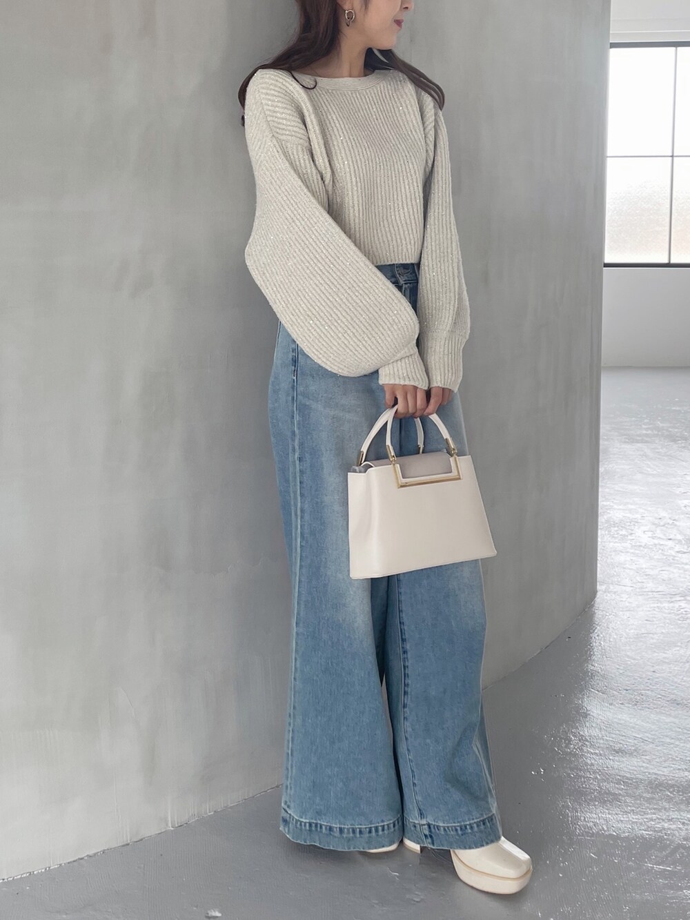 ホワイト系のブーツ、ホワイト系のハンドバッグ、ブルー系のデニムパンツを着用したレディースの秋コーディネートの4枚目の写真