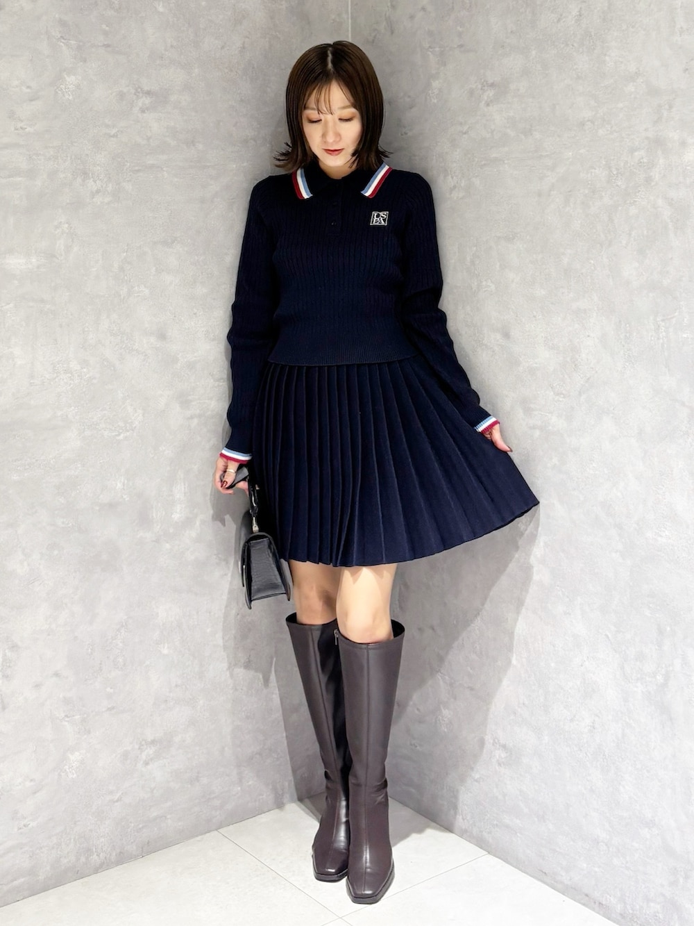 ブルー系のワンピース、ブラック系のハンドバッグ、ブラウン系のブーツを着用したレディースの冬コーディネートの5枚目の写真