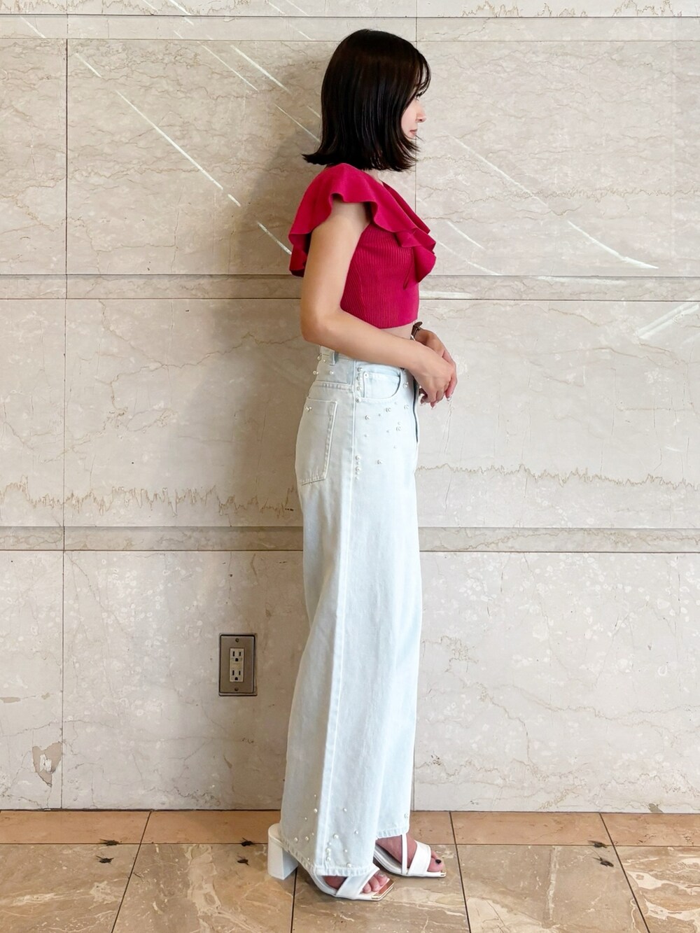 ブルー系のデニムパンツ、ホワイト系のサンダル、レッド系のニット/セーターを着用したレディースの夏コーディネートの2枚目の写真