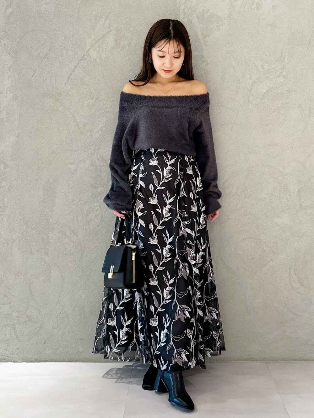 グレー系のスカート、ブラック系のブーツ、ブラック系のショルダーバッグを着用したレディースの秋コーディネートの9枚目の写真