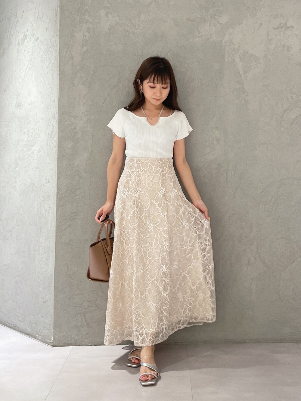 ブラウン系のトートバッグ、ホワイト系のニット/セーター、ベージュ系のスカートを着用したレディースの夏コーディネートの7枚目の写真