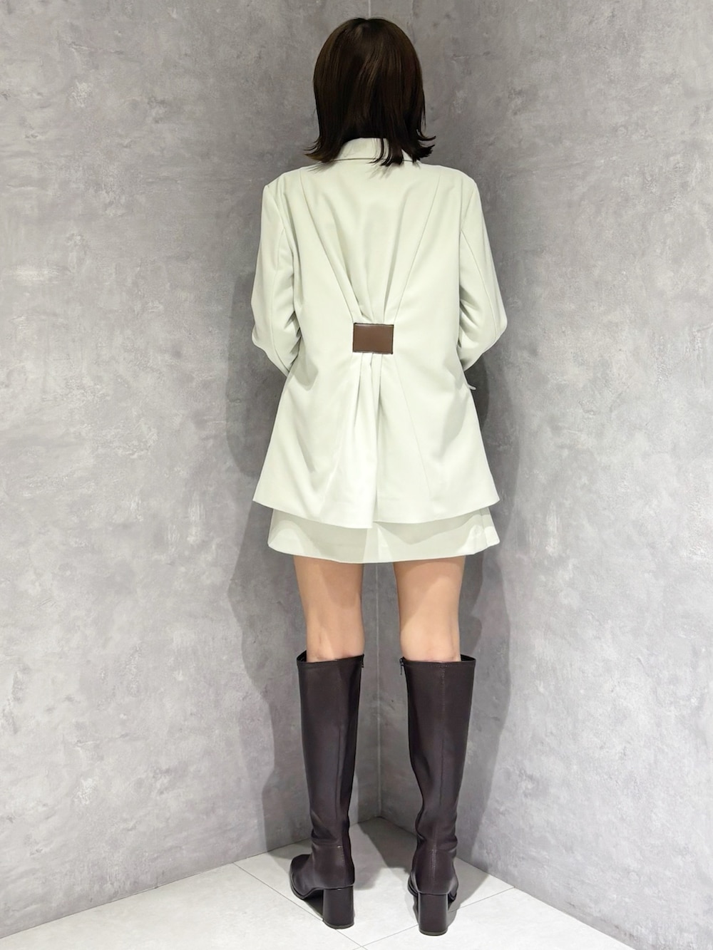 グリーン系のスカート、ブラウン系のブーツ、グリーン系のテーラードジャケットを着用したレディースの春コーディネートの2枚目の写真