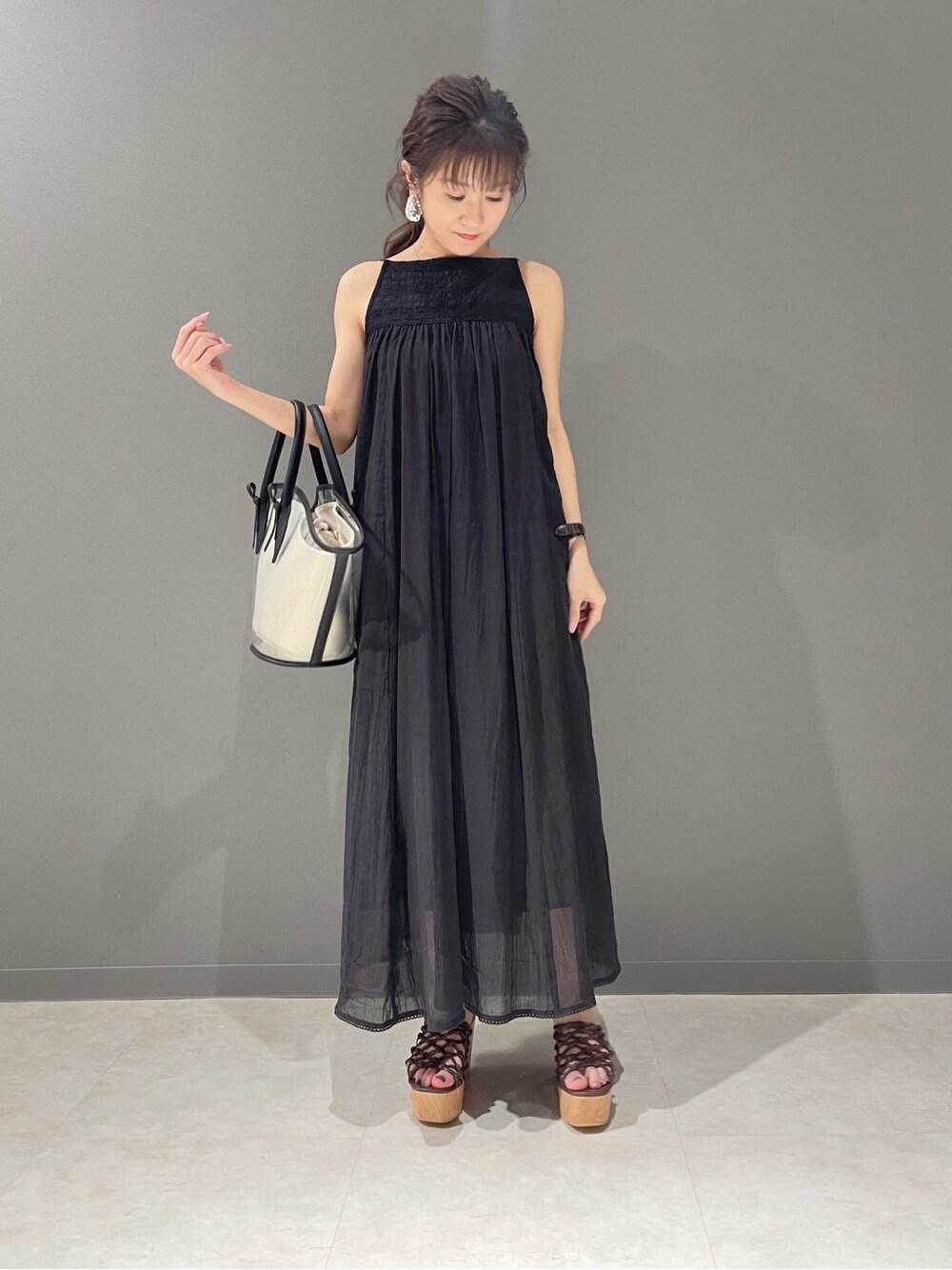 ブラック系のトートバッグ、ブラック系のワンピース、ブラウン系のサンダルを着用したレディースの春コーディネートの4枚目の写真