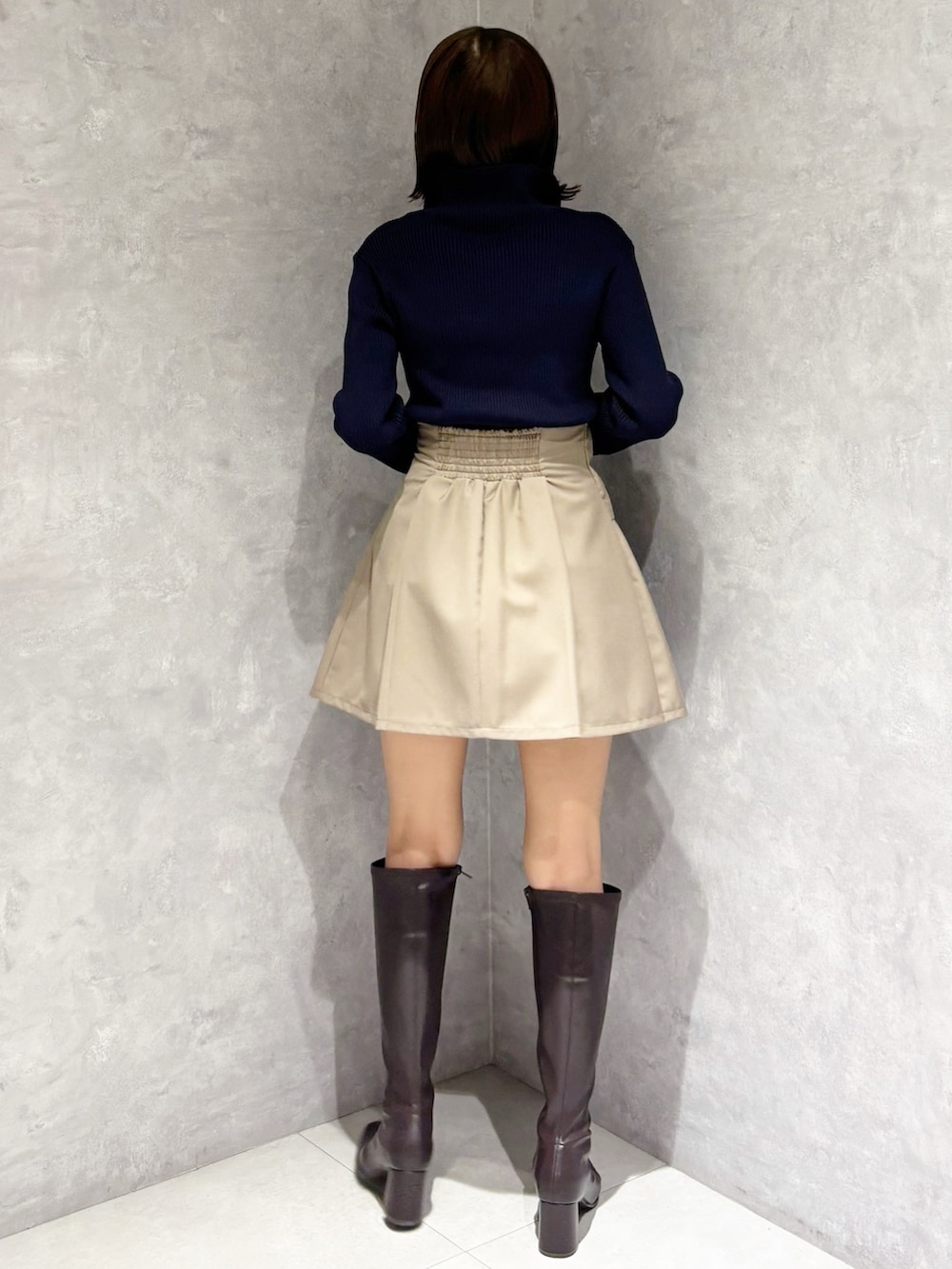 ベージュ系のスカート、ブラウン系のブーツ、ブラック系のハンドバッグを着用したレディースの冬コーディネートの2枚目の写真