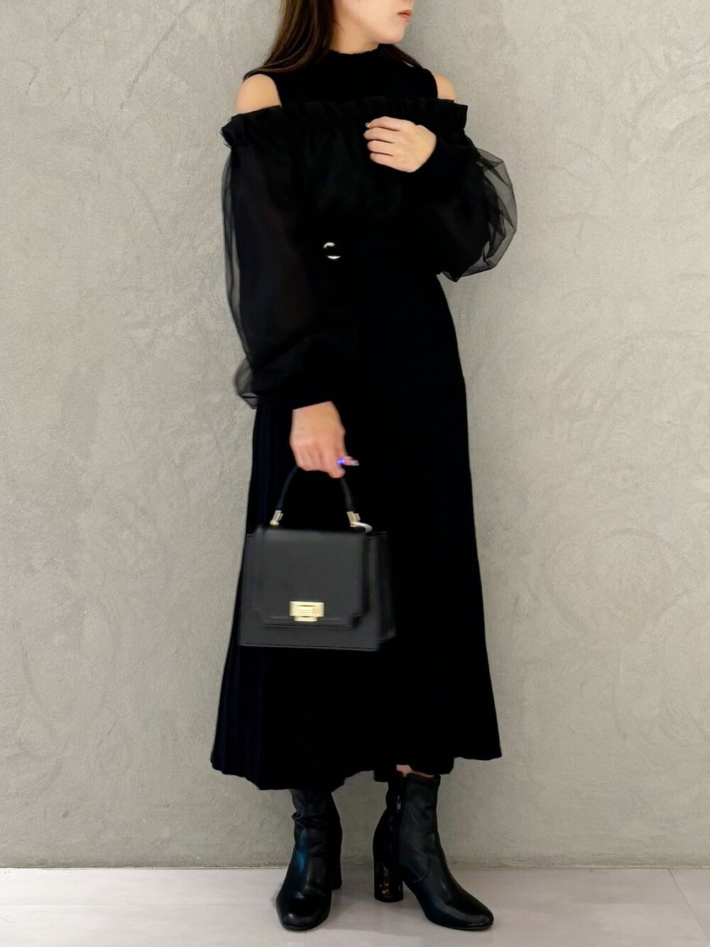 ブラック系のワンピース、ブラック系のブーツ、ブラック系のハンドバッグを着用したレディースの秋コーディネートの3枚目の写真