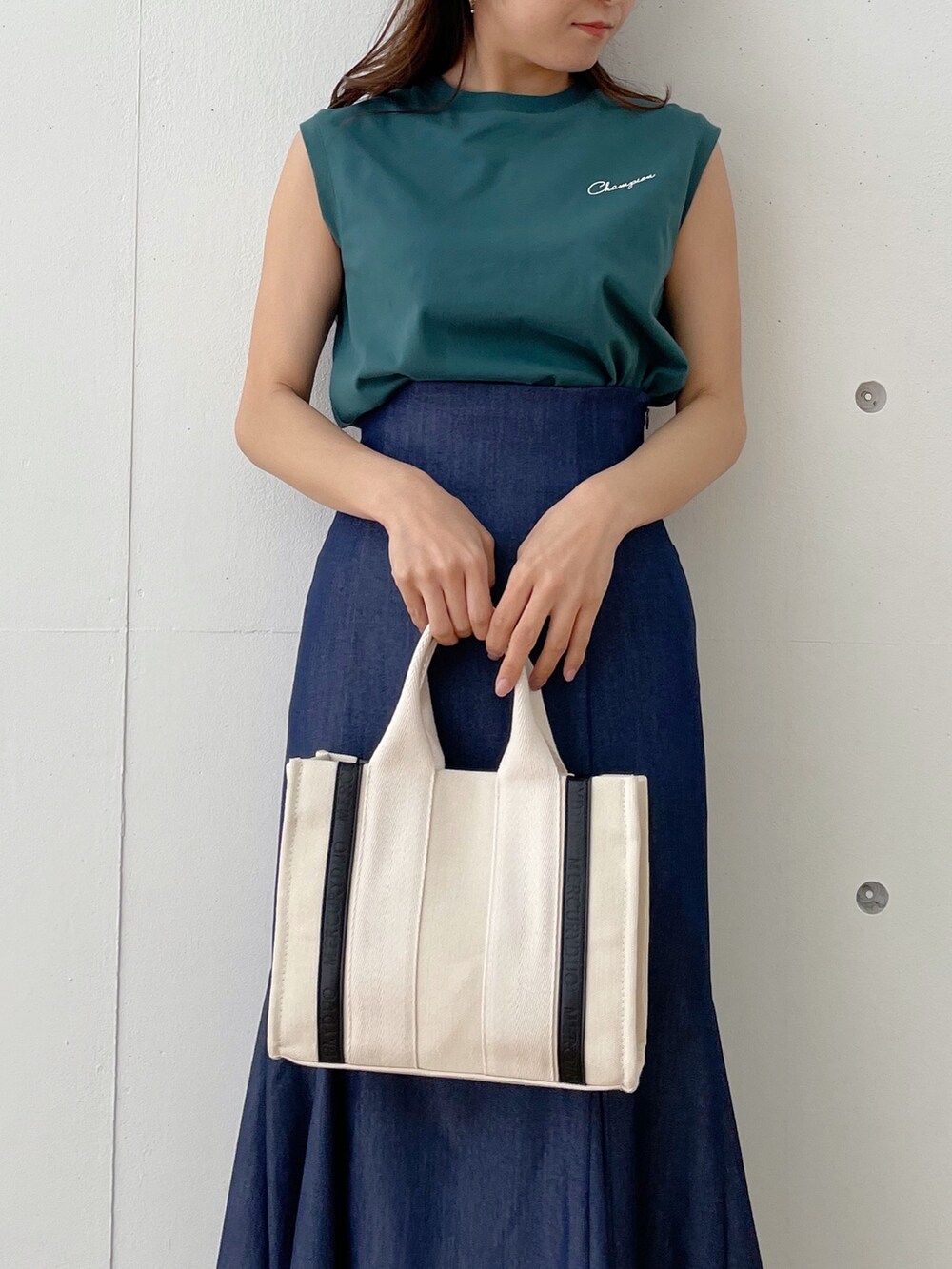 グレー系のハンドバッグ、ブラック系のサンダル、ブルー系のスカートを着用したレディースの春コーディネートの3枚目の写真