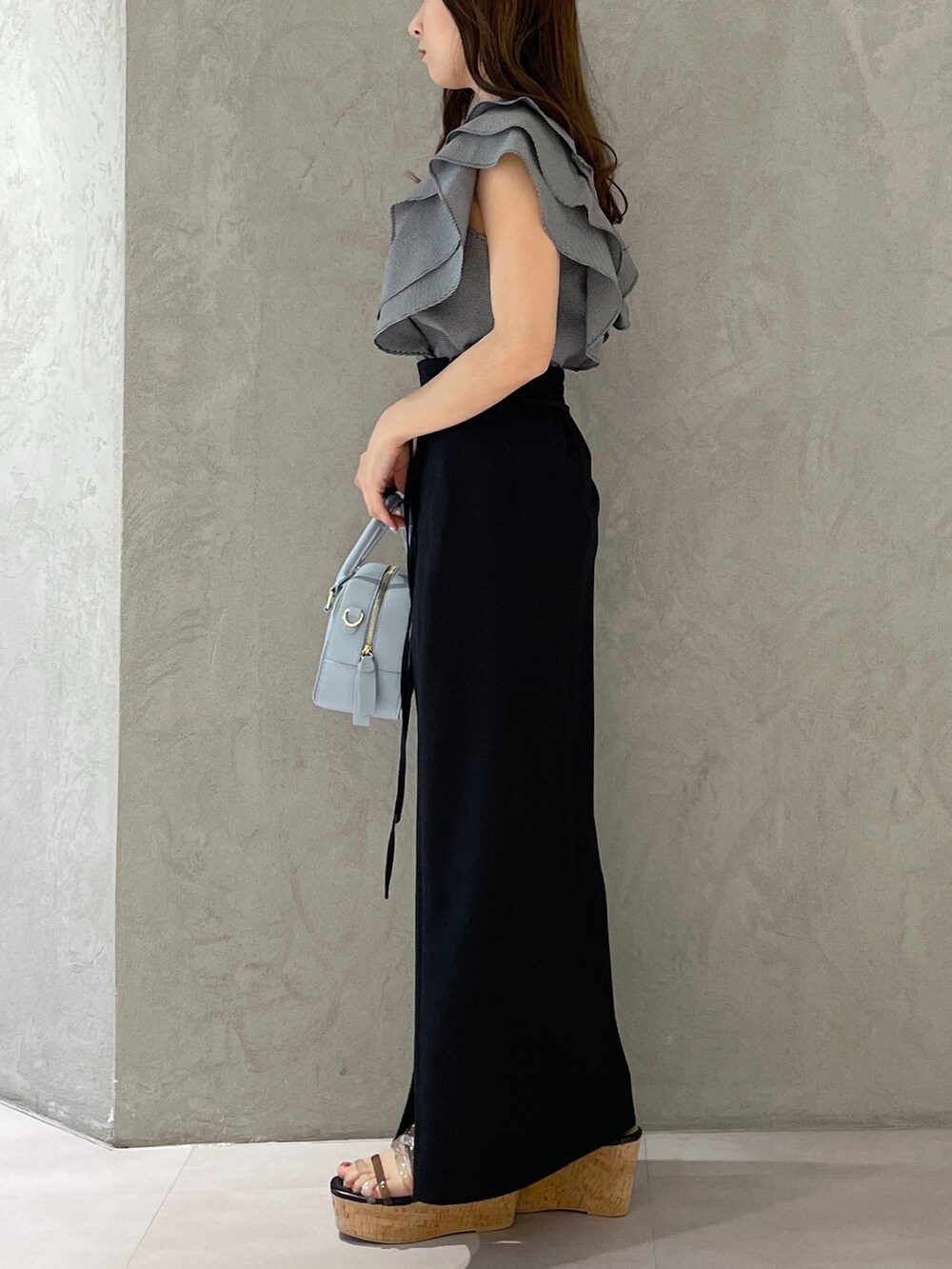 ブラック系のスカート、ブラック系のサンダル、ブルー系のボストンバッグを着用したレディースの春コーディネートの4枚目の写真