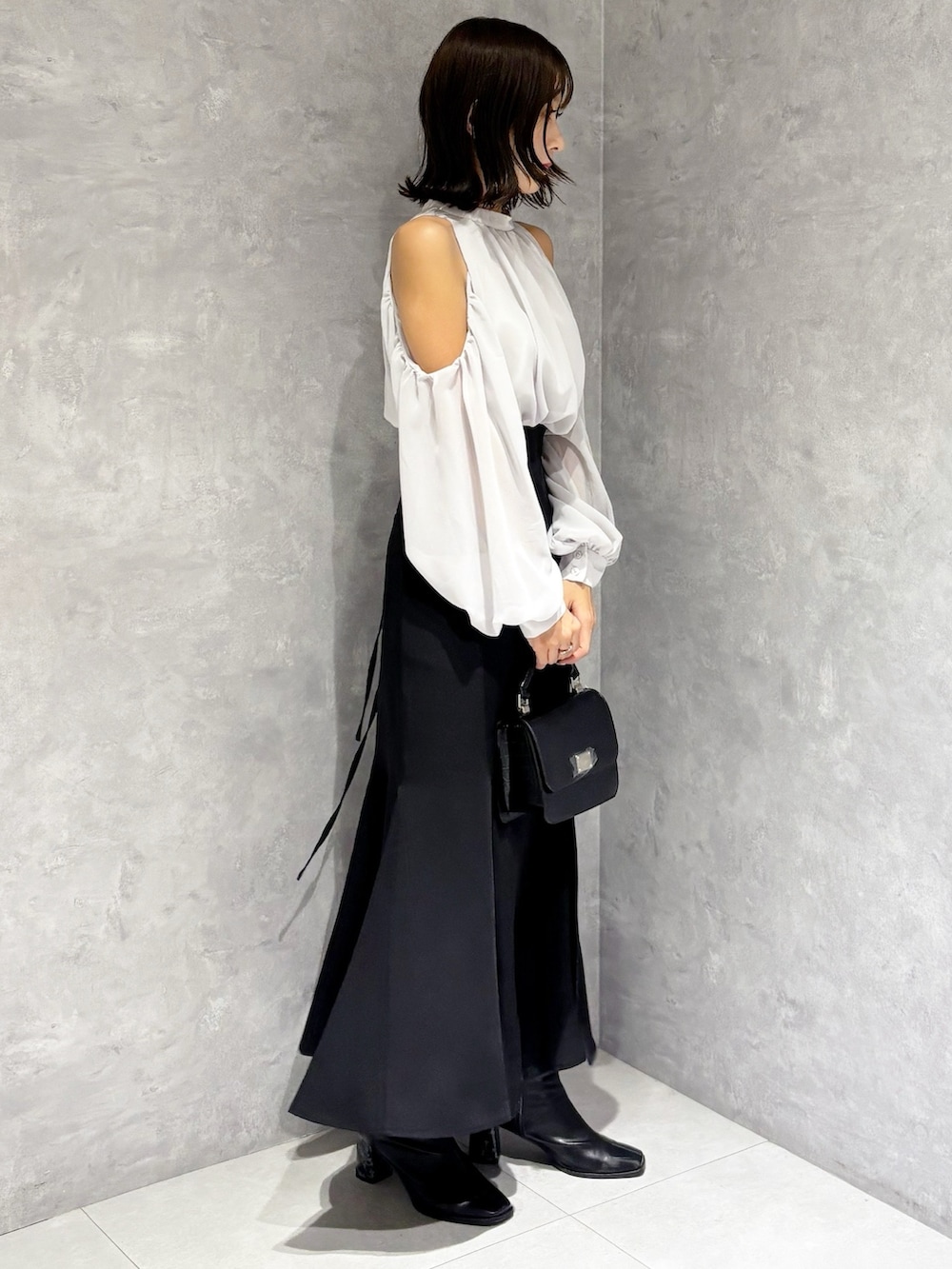 ブラック系のハンドバッグ、ブラック系のブーツ、ブラック系のスカートを着用したレディースの秋コーディネートの6枚目の写真