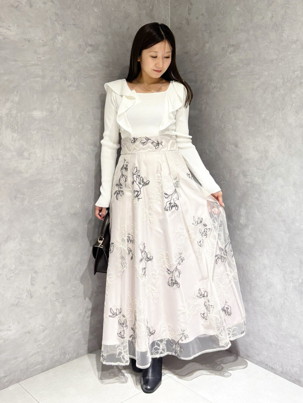 ブラウン系のハンドバッグ、ブラック系のブーツ、ベージュ系のスカートを着用したレディースの冬コーディネートの6枚目の写真