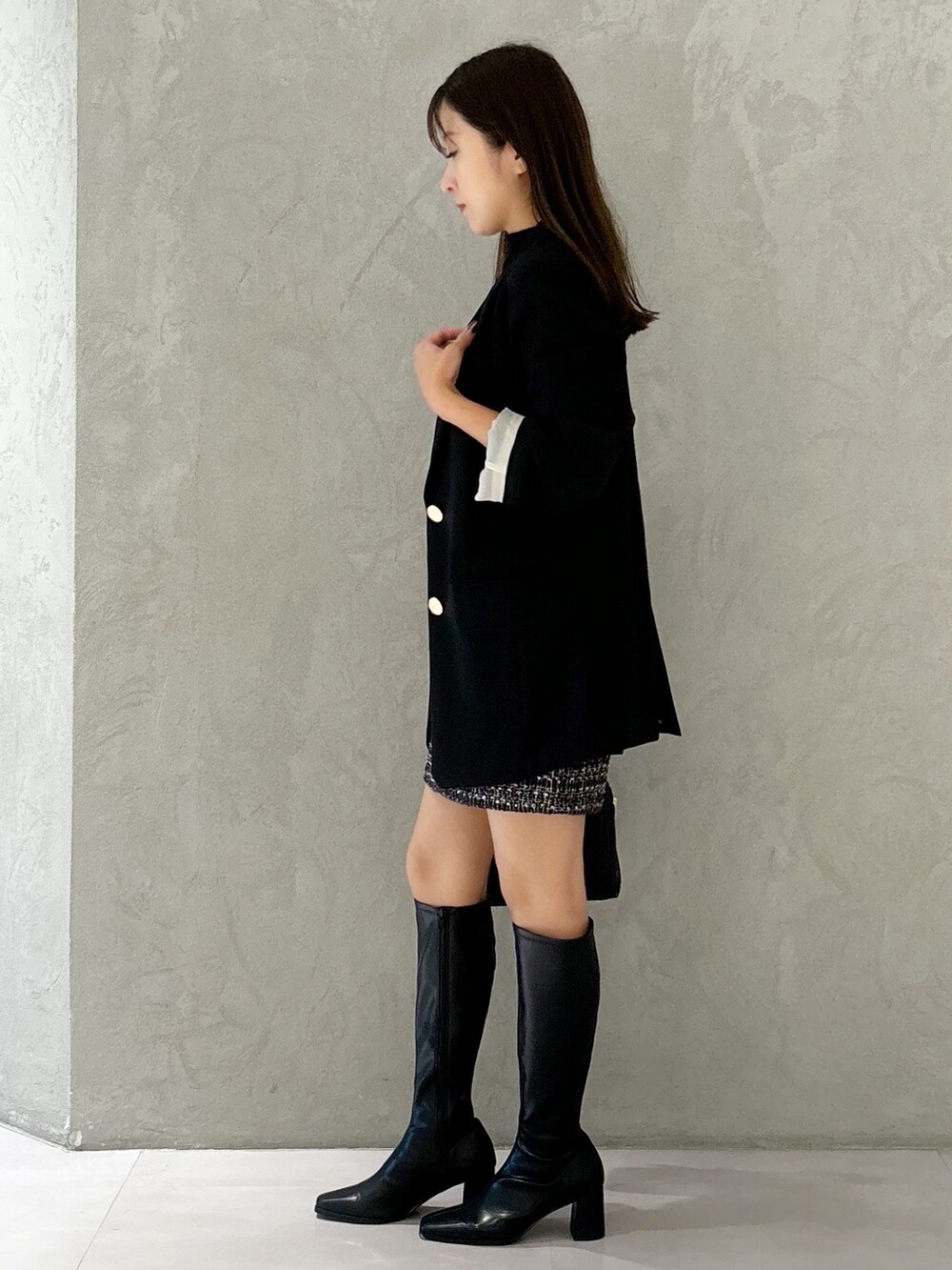 ブラック系のスカート、ブラック系のブーツ、ブラック系のショルダーバッグを着用したレディースの秋コーディネートの2枚目の写真