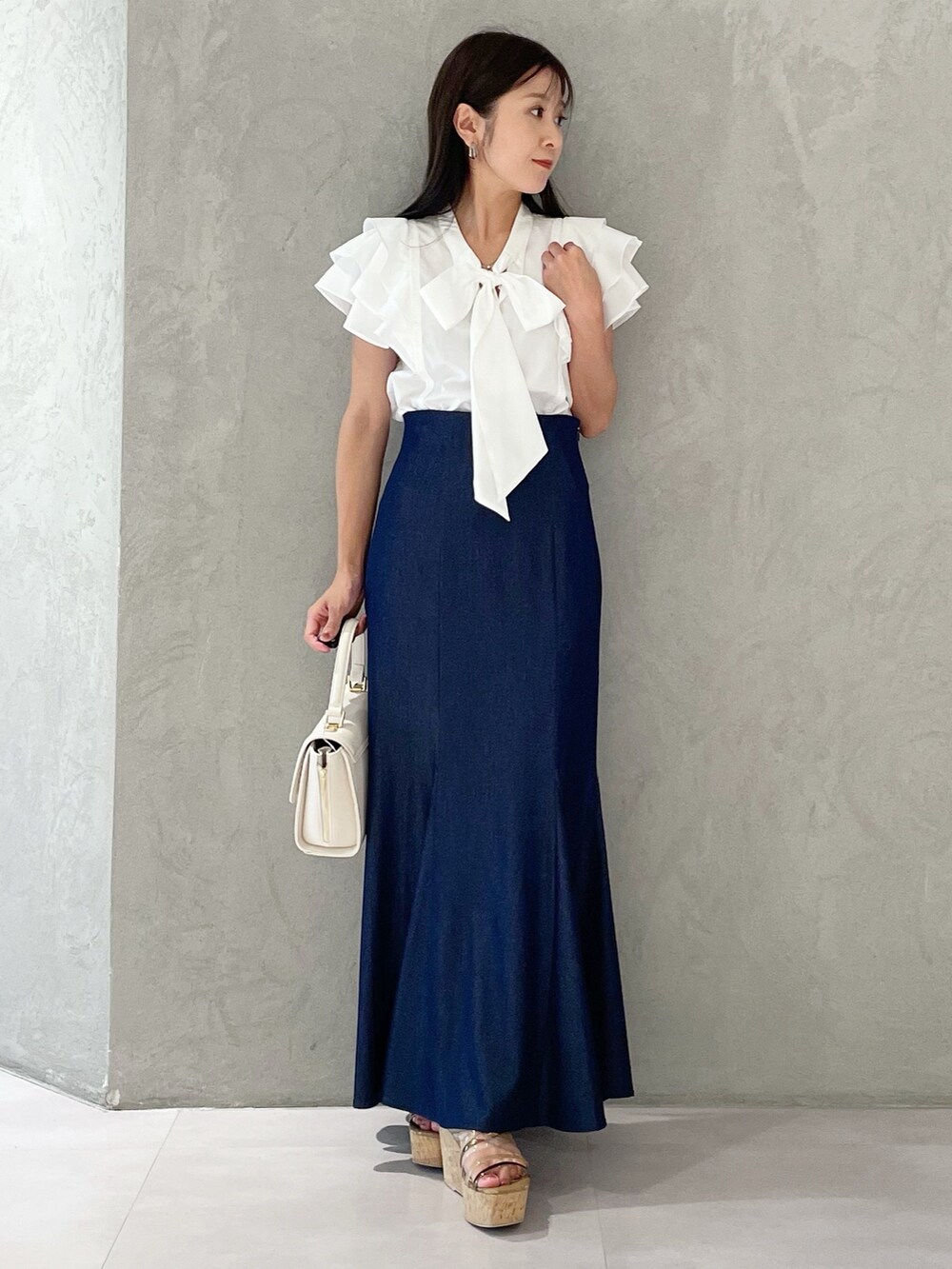 ブルー系のスカート、ブラウン系のサンダル、ホワイト系のショルダーバッグを着用したレディースの夏コーディネートの5枚目の写真