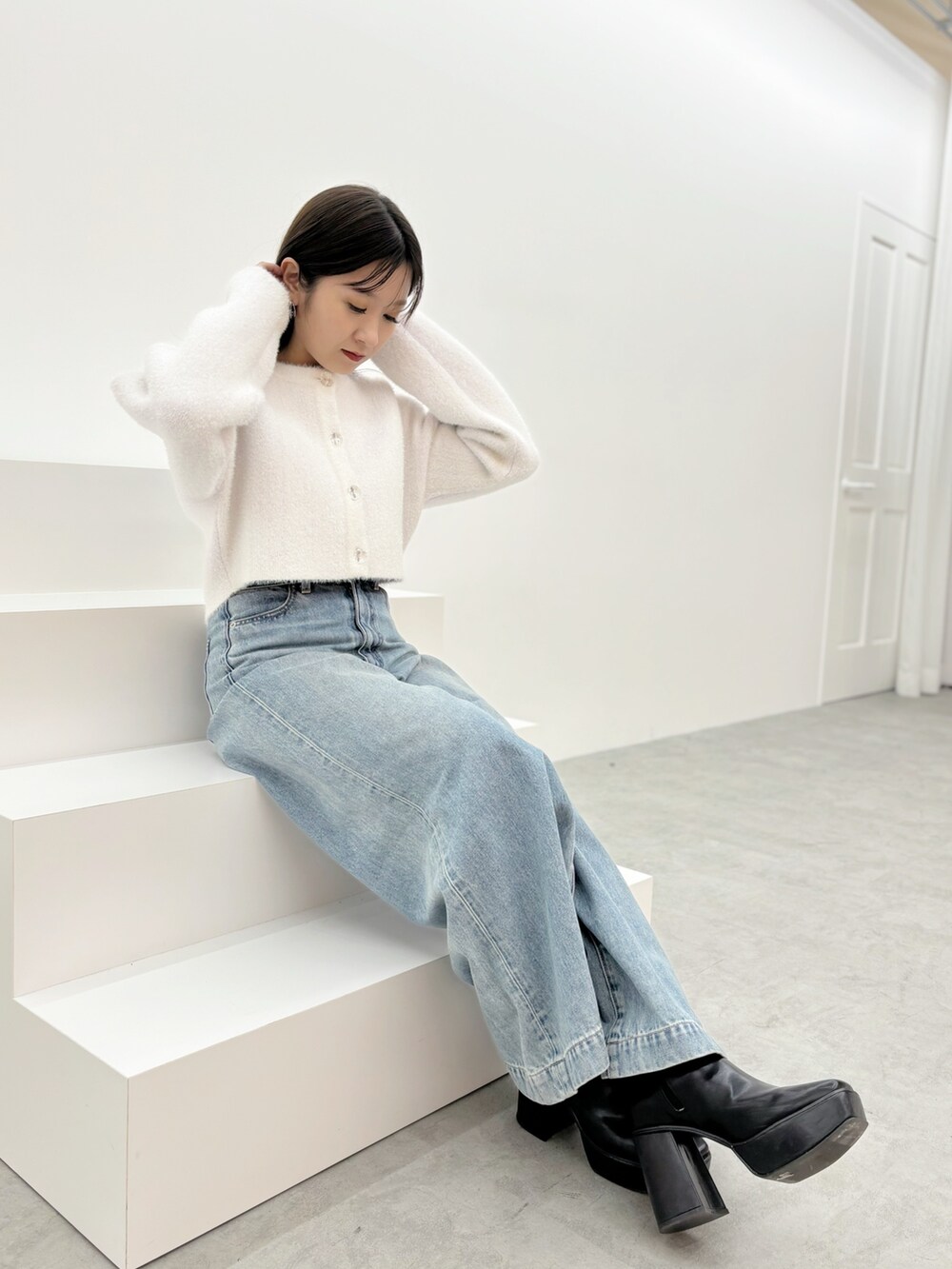 ブルー系のデニムパンツ、ブラック系のブーツ、ホワイト系のカーディガン/ボレロを着用したレディースの秋コーディネートの9枚目の写真