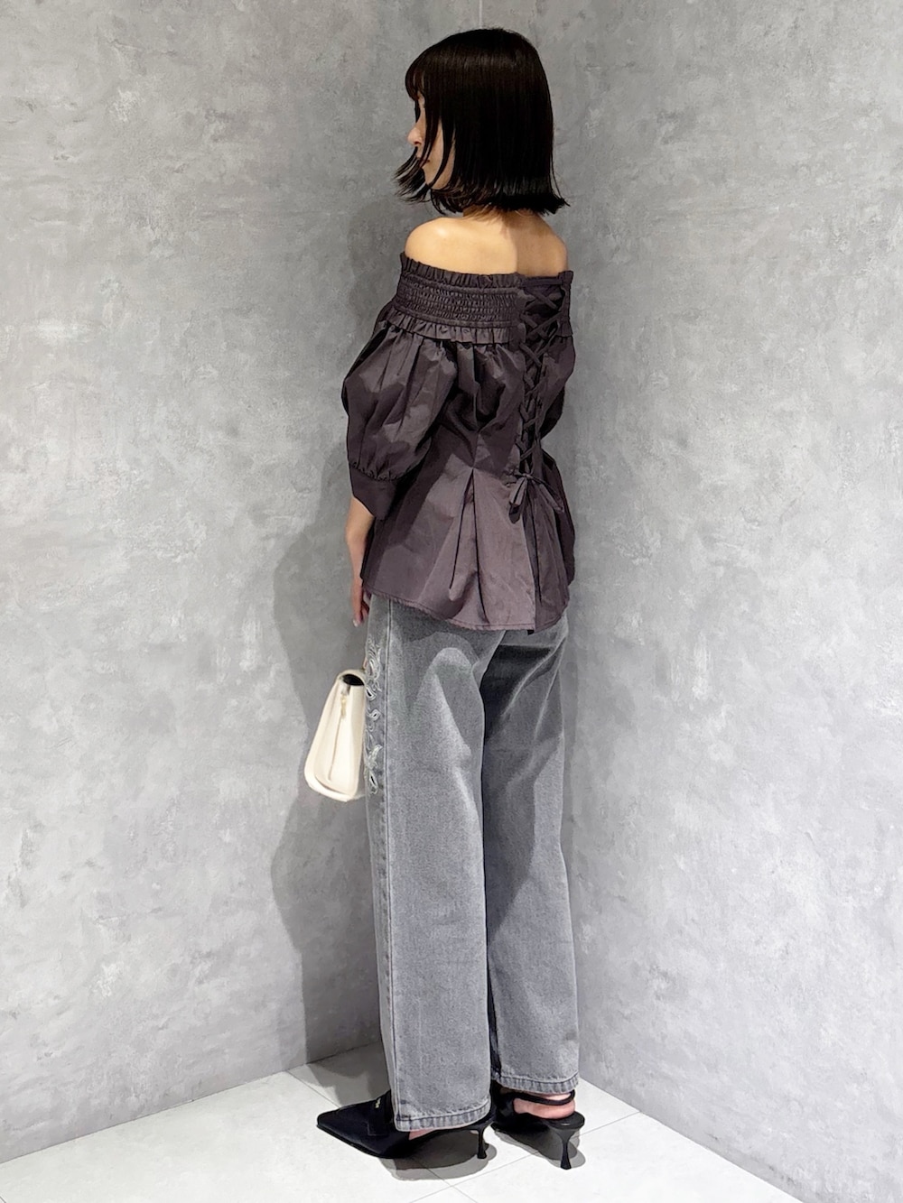 ホワイト系のハンドバッグ、ブラック系のパンプス、グレー系のデニムパンツを着用したレディースの夏コーディネートの5枚目の写真