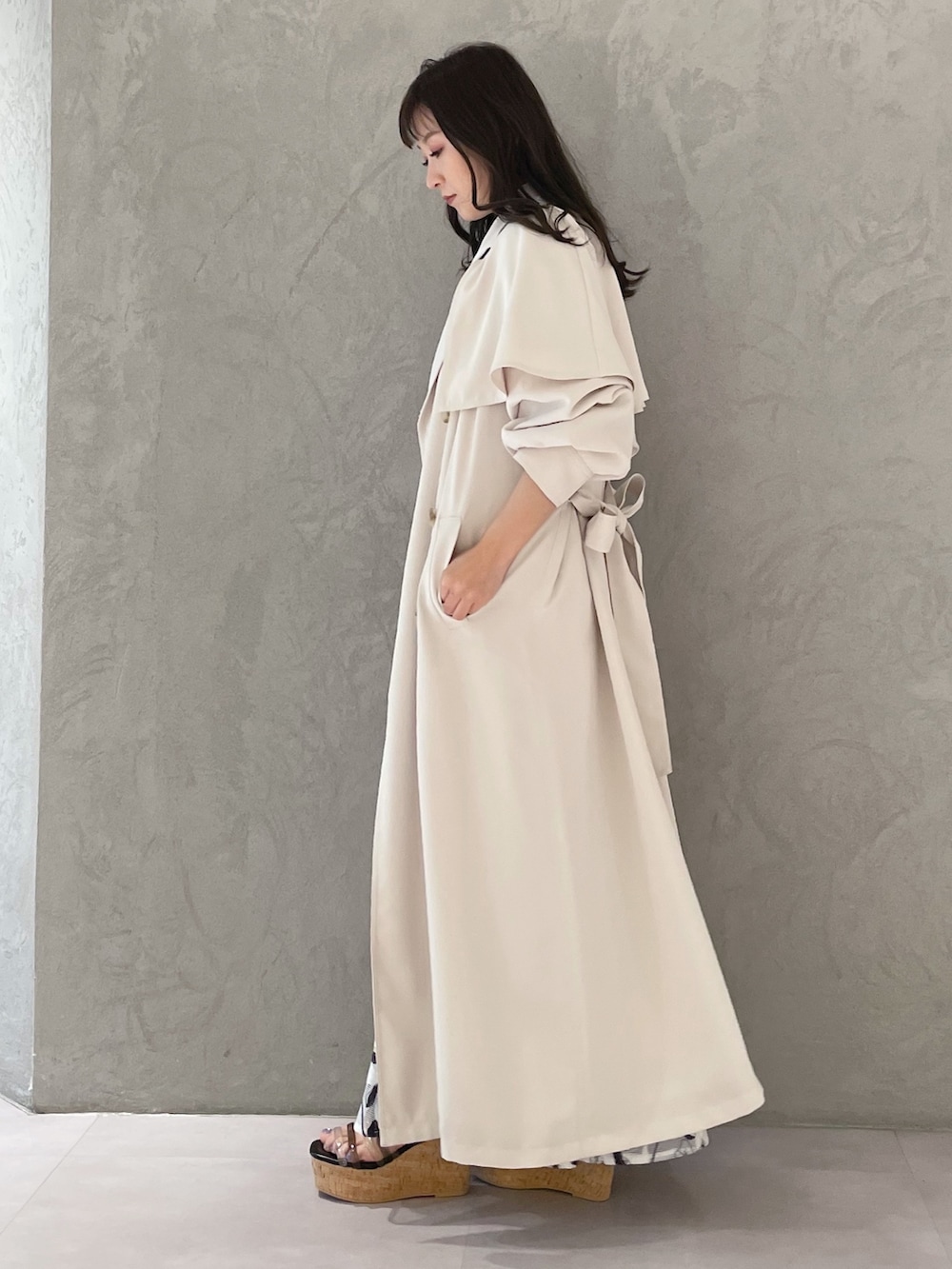 ホワイト系のスカート、ブルー系のニット/セーター、ホワイト系のトレンチコートを着用したレディースの春コーディネートの3枚目の写真