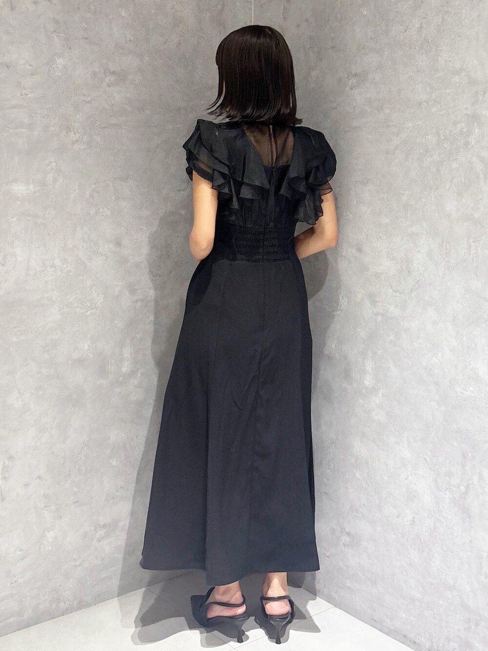 ブラック系のワンピース、ブラック系のパンプス、ホワイト系のハンドバッグを着用したレディースの夏コーディネートの2枚目の写真