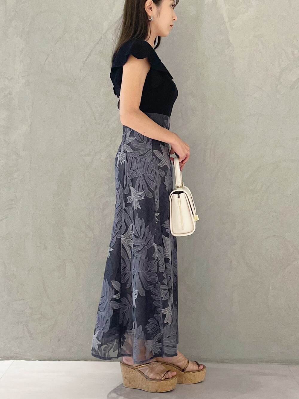 ブラック系のニット/セーター、ホワイト系のショルダーバッグ、ブラウン系のサンダルを着用したレディースの夏コーディネートの2枚目の写真