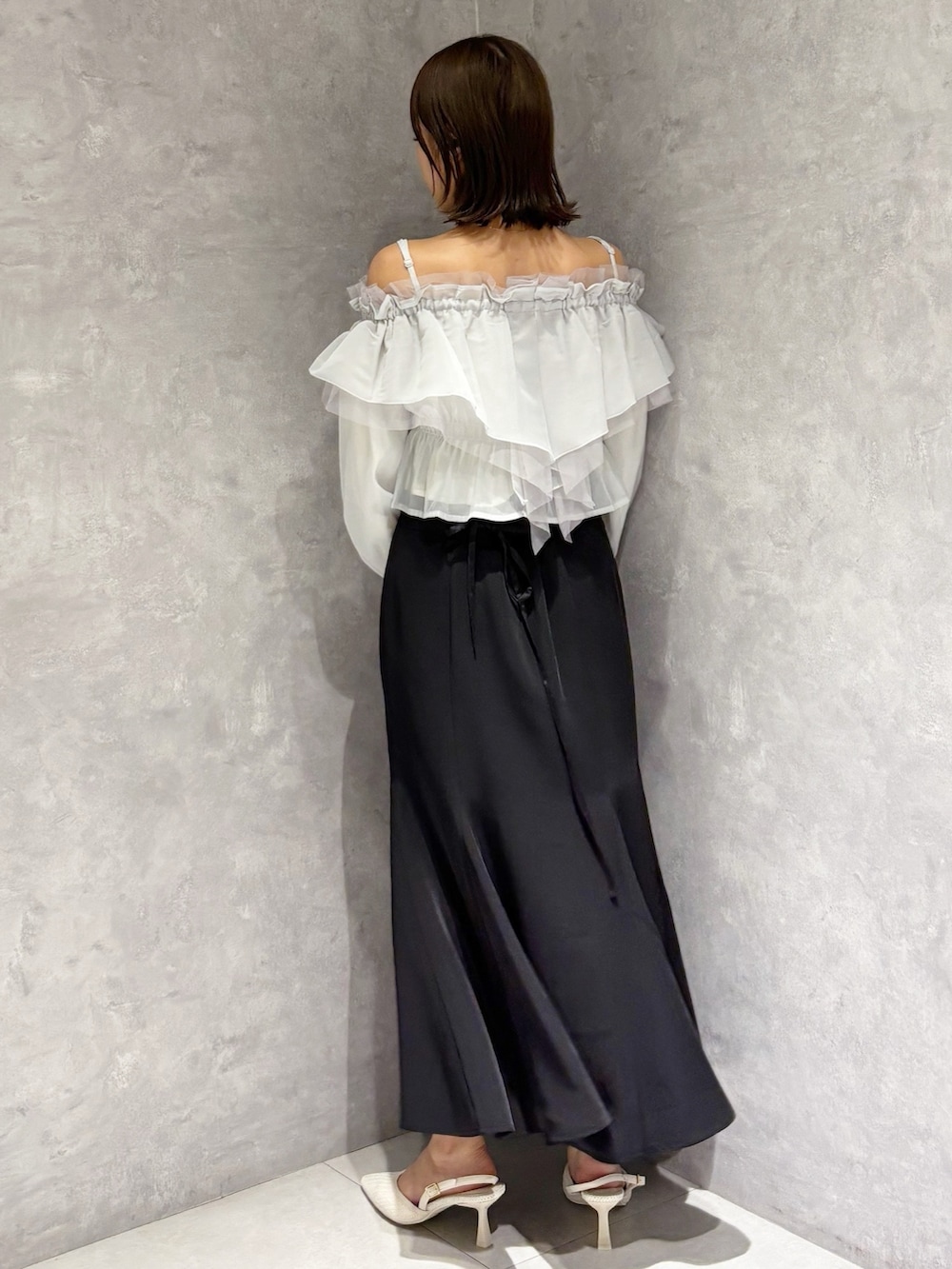 ブラック系のスカート、ホワイト系のパンプス、グリーン系のシャツ/ブラウスを着用したレディースの春コーディネートの3枚目の写真