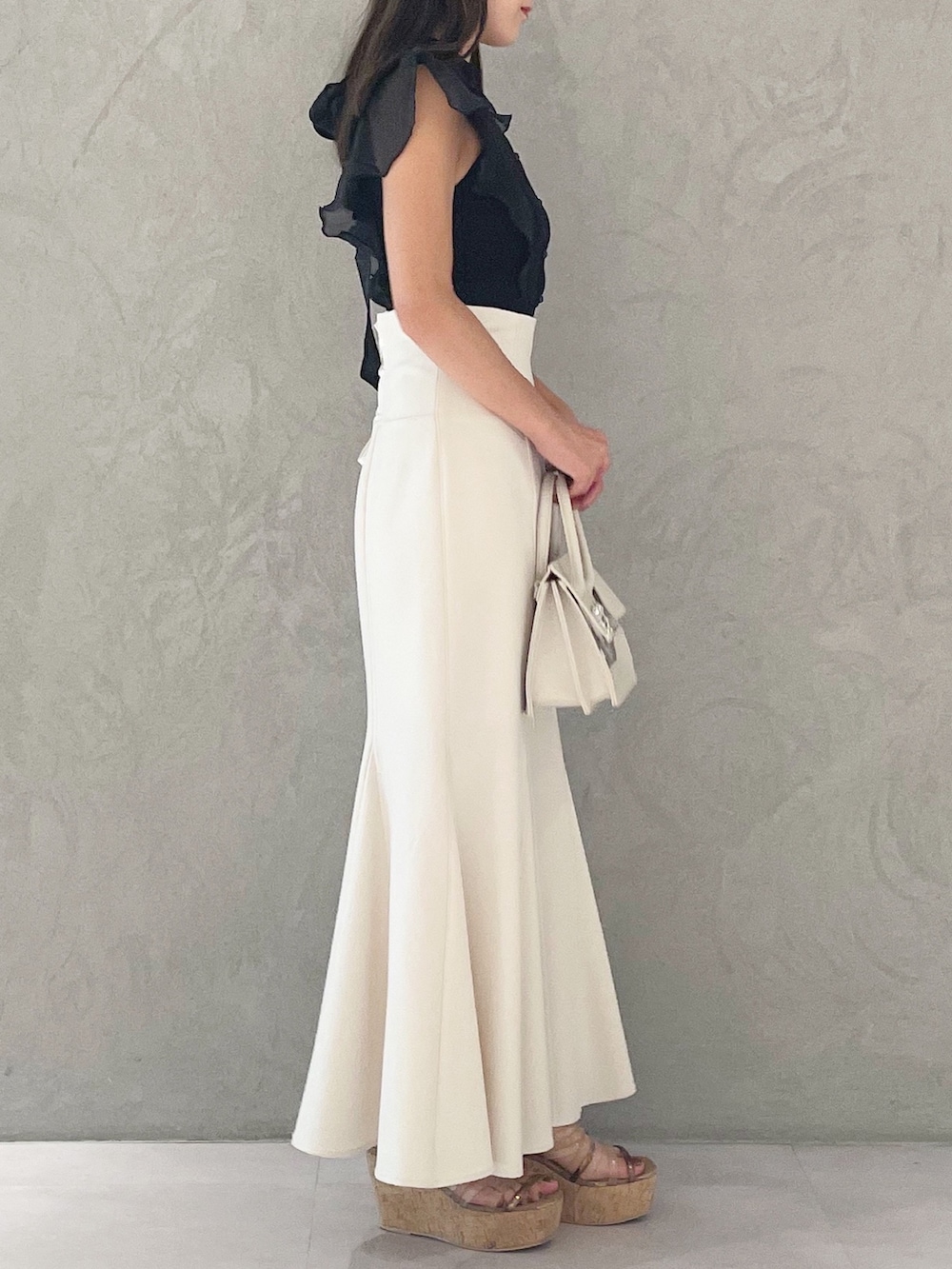 ブラック系のニット/セーター、ホワイト系のスカート、ブラウン系のサンダルを着用したレディースの夏コーディネートの5枚目の写真