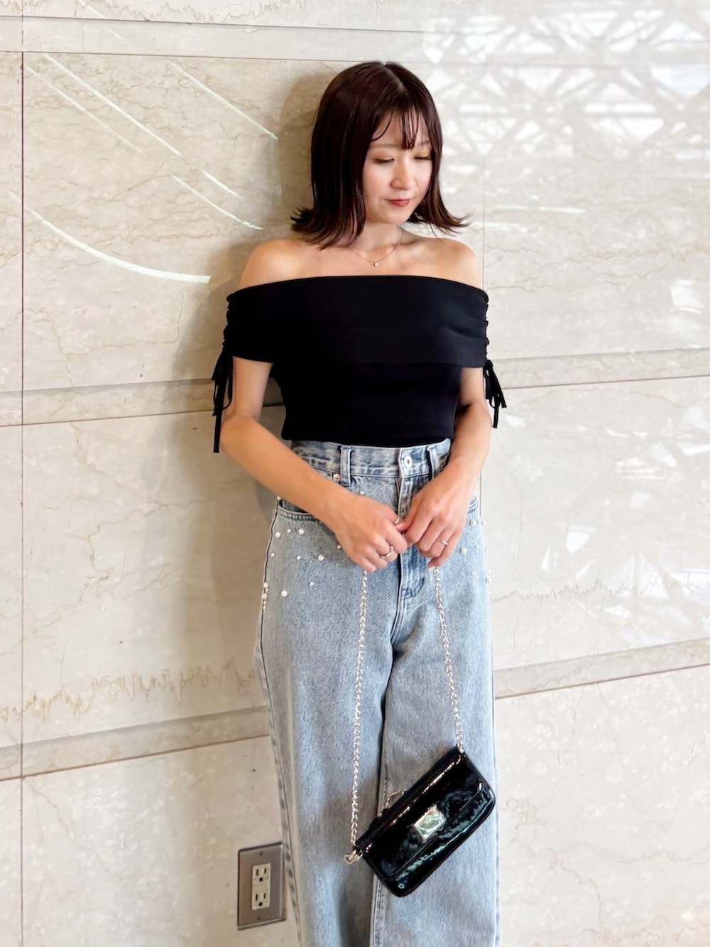 ブラック系のボディバッグ/ウエストポーチ、ブラック系のニット/セーター、ブルー系のデニムパンツを着用したレディースの夏コーディネートの5枚目の写真