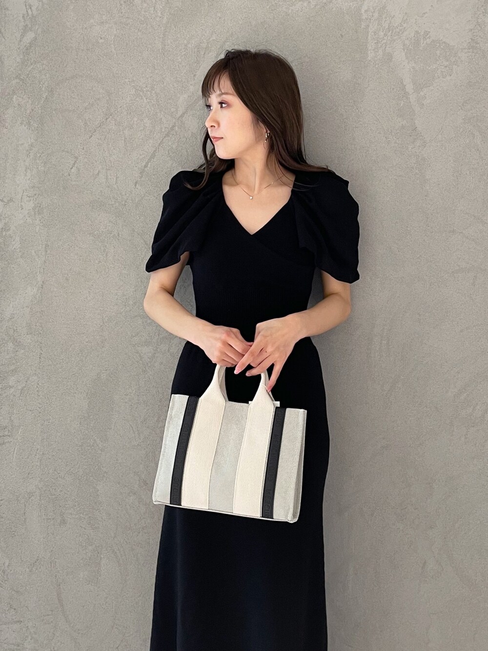 グレー系のワンピース、シルバー系のサンダル、グレー系のハンドバッグを着用したレディースの春コーディネートの5枚目の写真