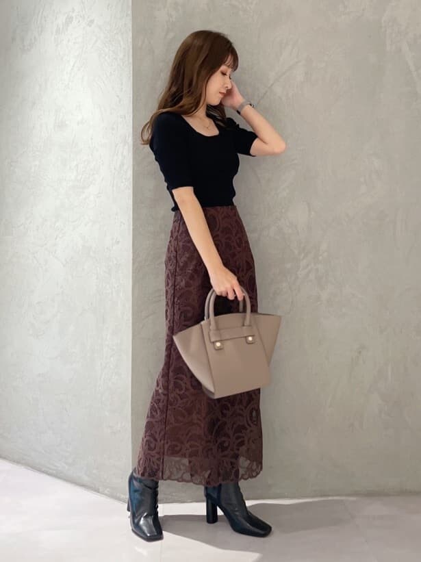 ブラウン系のハンドバッグ、ブラック系のニット/セーター、ブラック系のブーツを着用したレディースの夏コーディネートの7枚目の写真