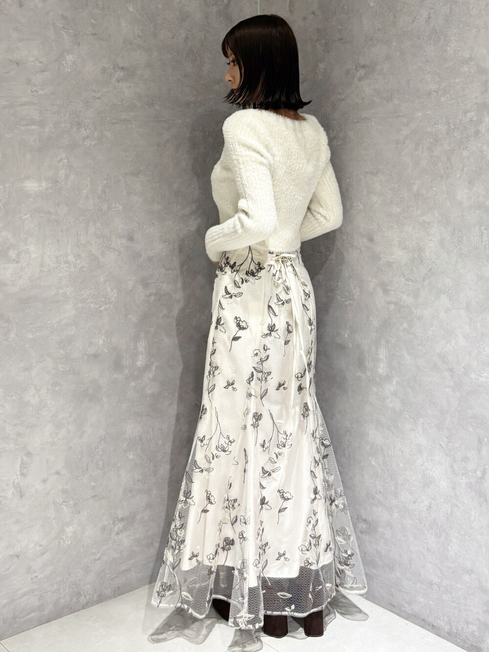 ホワイト系のスカート、ブラウン系のブーツ、ホワイト系のニット/セーターを着用したレディースの秋コーディネートの3枚目の写真