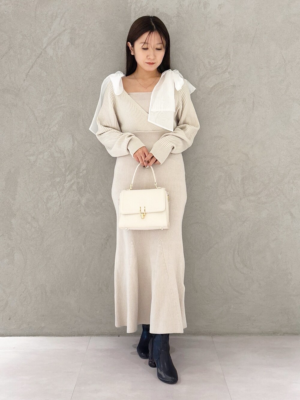 ホワイト系のハンドバッグ、ブラック系のブーツ、ホワイト系のワンピースを着用したレディースの冬コーディネートの8枚目の写真