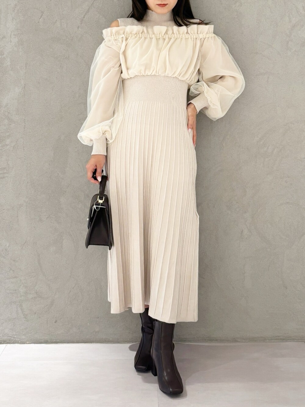 ホワイト系のワンピース、ブラウン系のブーツ、ブラウン系のハンドバッグを着用したレディースの冬コーディネートの7枚目の写真