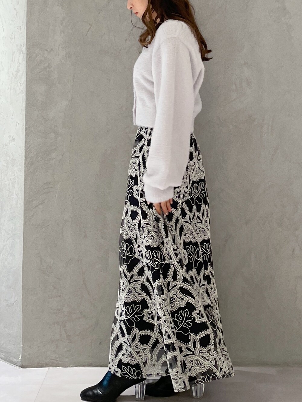 ブラック系のスカート、グレー系のカーディガン/ボレロ、ブラック系のブーツを着用したレディースの冬コーディネートの3枚目の写真