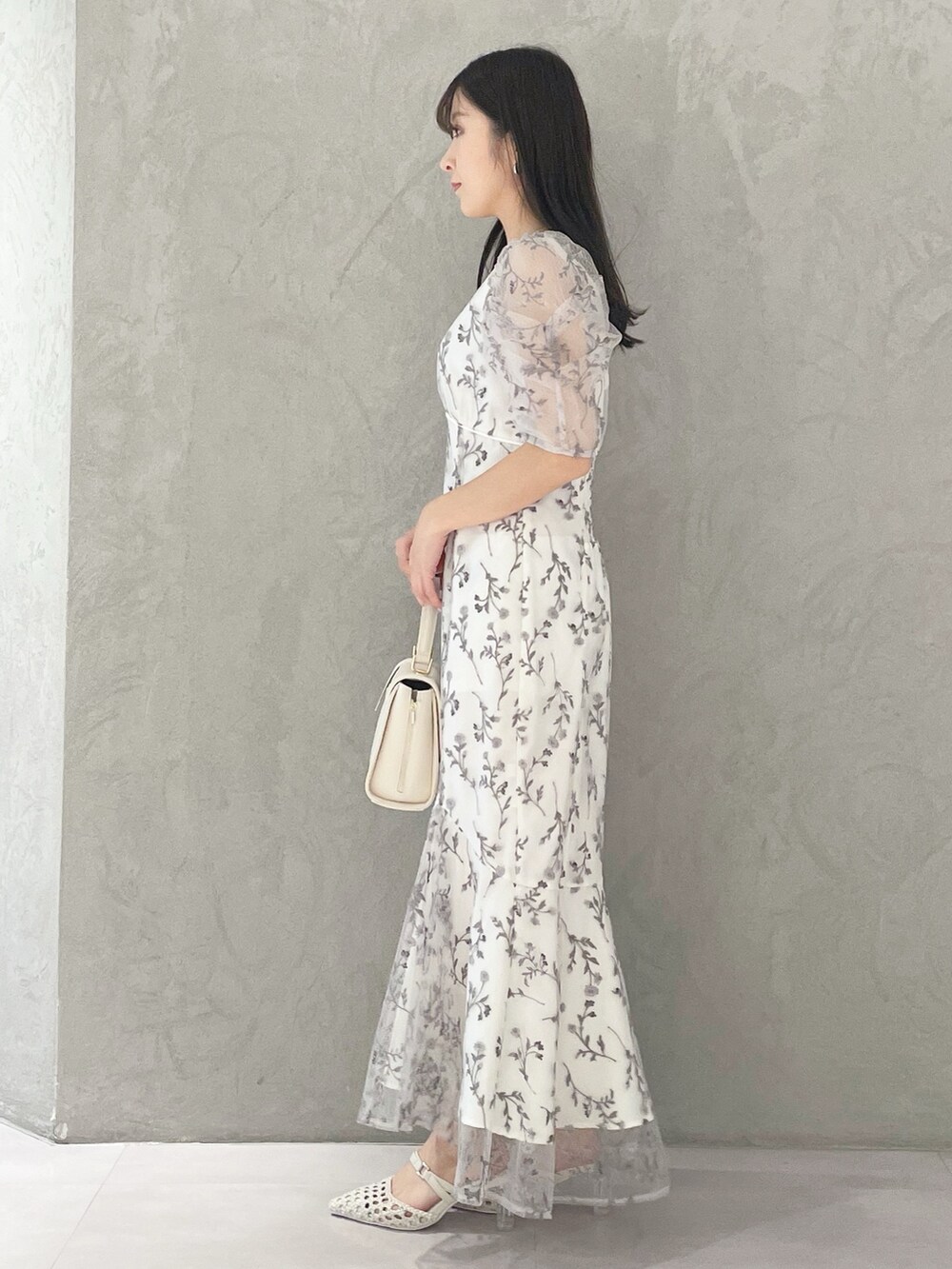 ホワイト系のショルダーバッグ、ホワイト系のパンプス、グレー系のワンピースを着用したレディースの春コーディネートの2枚目の写真