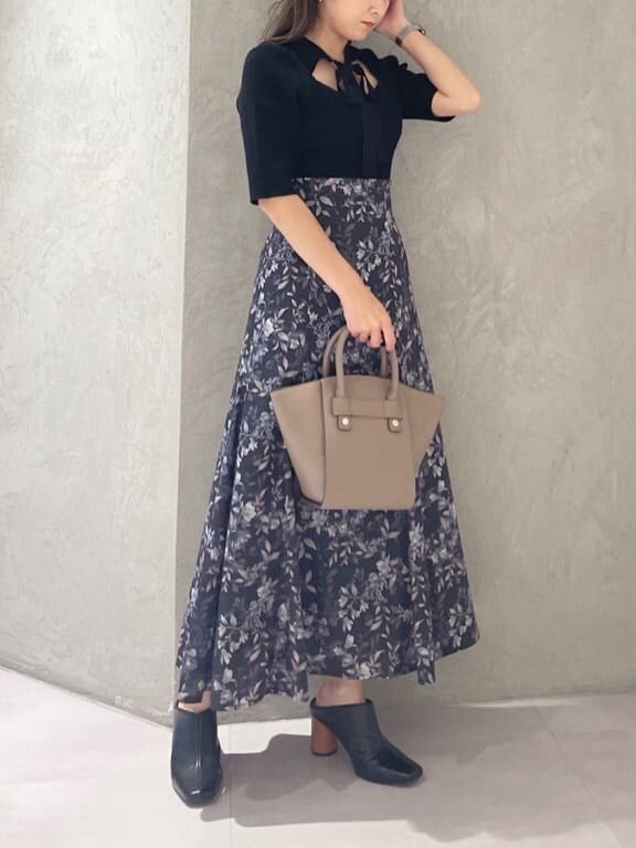 ブラック系のニット/セーター、ブラウン系のハンドバッグ、ブルー系のスカートを着用したレディースの夏コーディネートの3枚目の写真