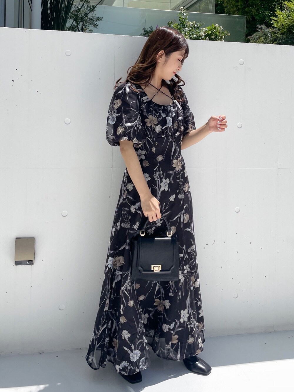 ブラック系のハンドバッグ、ブラック系のワンピースを着用したレディースの夏コーディネートの2枚目の写真