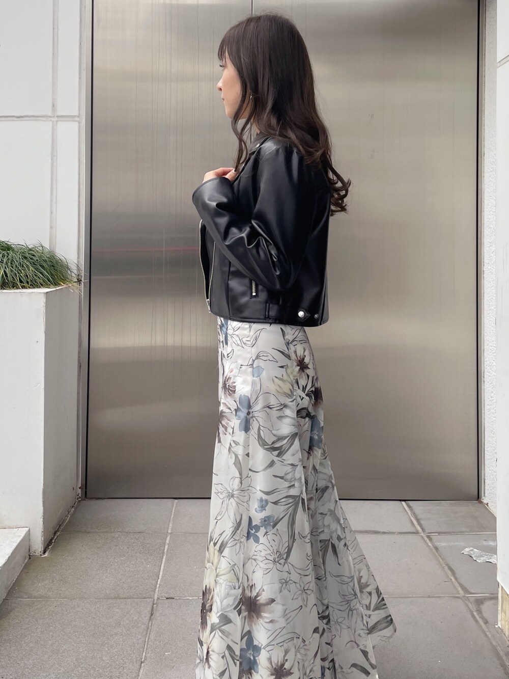 グリーン系のスカート、ブラック系のライダースジャケット、ブラック系のニット/セーターを着用したレディースの冬コーディネートの3枚目の写真