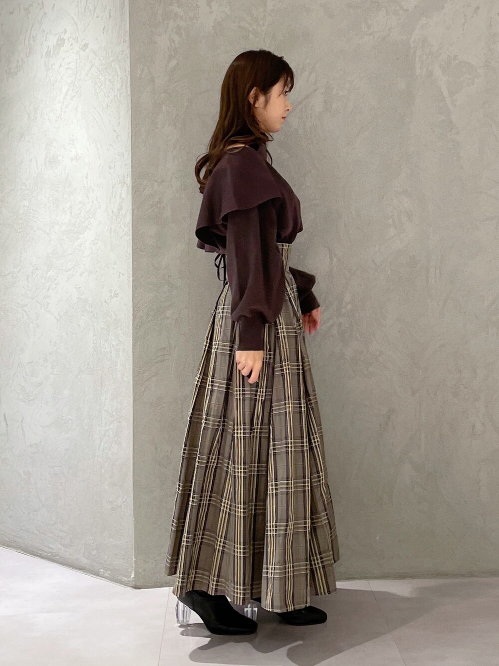 ベージュ系のスカート、ブラウン系のニット/セーター、ブラック系のブーツを着用したレディースの秋コーディネートの3枚目の写真