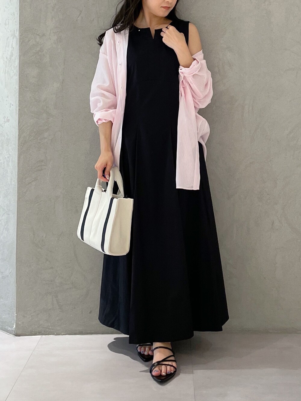 ブラック系のワンピース、ブラック系のサンダル、ホワイト系のハンドバッグを着用したレディースの春コーディネートの6枚目の写真