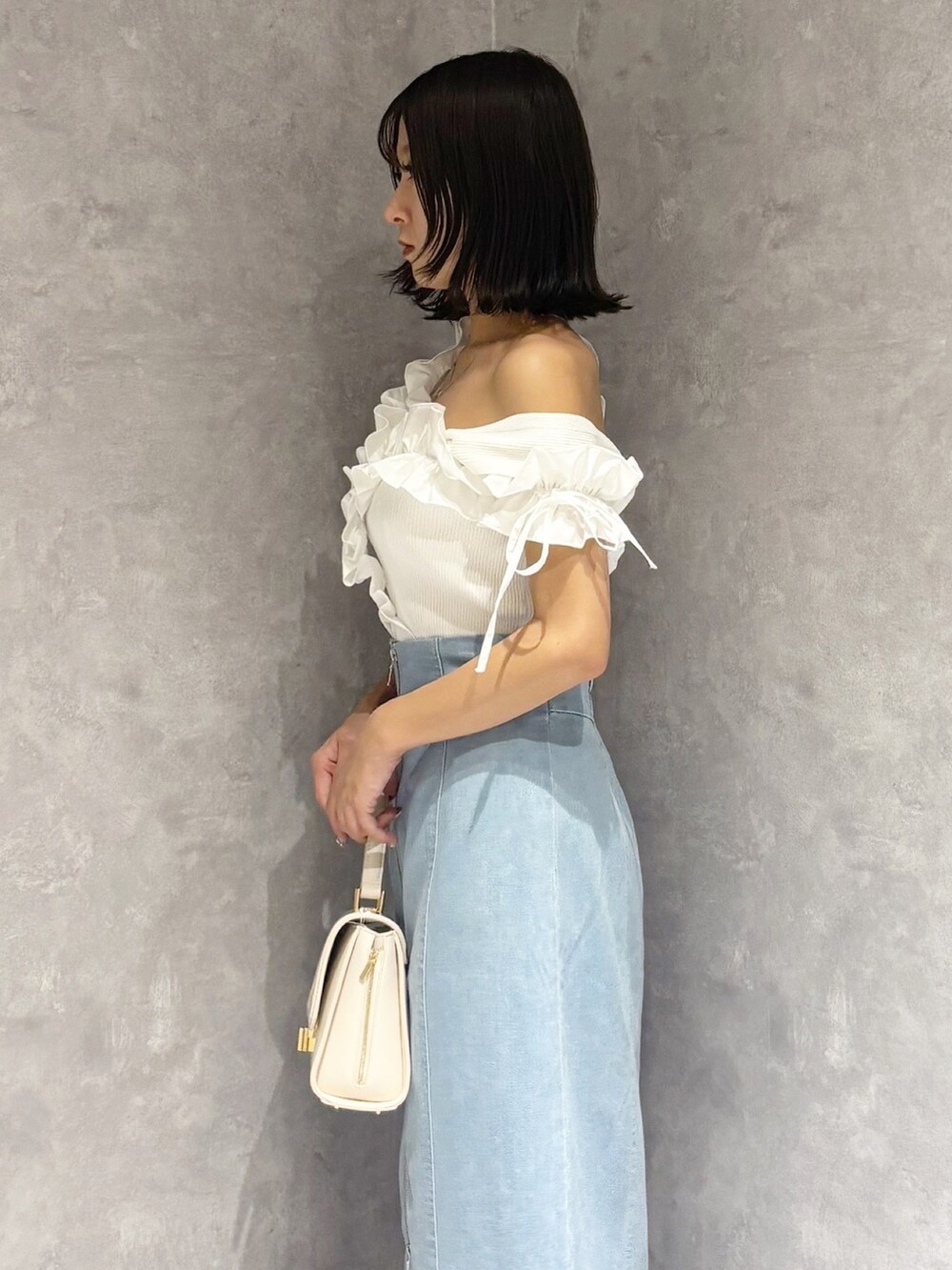 ブルー系のスカート、ベージュ系のサンダル、ホワイト系のハンドバッグを着用したレディースの夏コーディネートの3枚目の写真