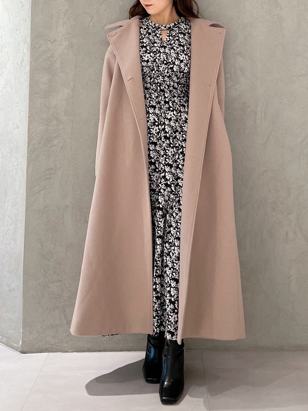 ブラック系のワンピース、ベージュ系のステンカラーコート、ブラック系のブーツを着用したレディースの秋コーディネートの4枚目の写真