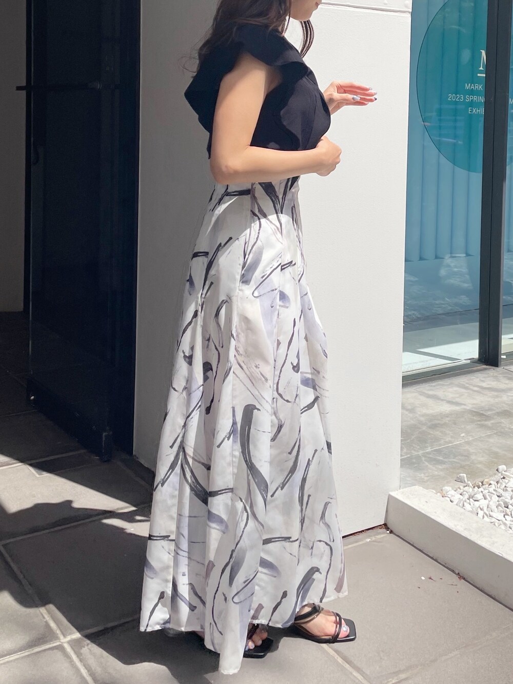 ブラック系のサンダル、ブラック系のニット/セーター、グレー系のスカートを着用したレディースの春コーディネートの3枚目の写真