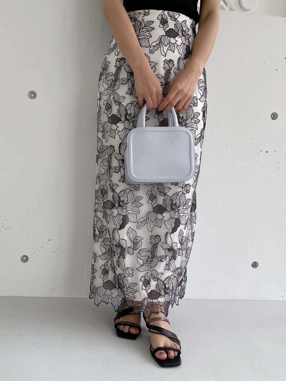 ホワイト系のスカート、ブラック系のニット/セーター、ブラック系のサンダルを着用したレディースの冬コーディネートの2枚目の写真