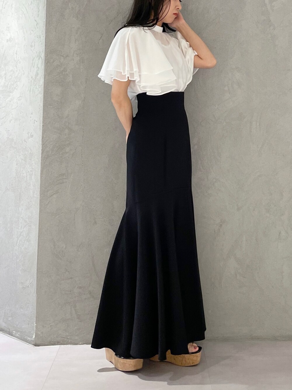 ブラック系のスカート、ブラック系のサンダル、ホワイト系のシャツ/ブラウスを着用したレディースの春コーディネートの2枚目の写真